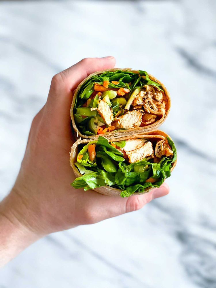 hand holding a wrap filled with tofu and lettuce